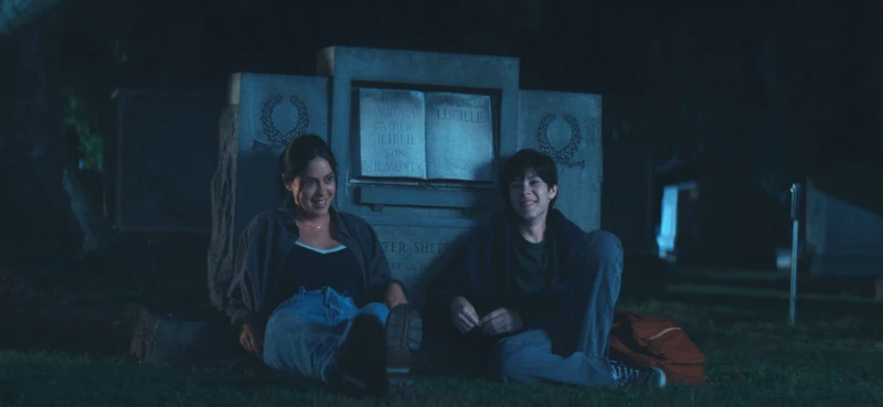 Rosa Salazar and Shylo Molina sitting together in a cemetery at night.