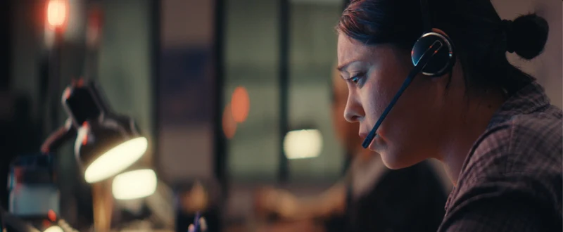 Rosa Salazar in profile at a desk beside a warm lamp.